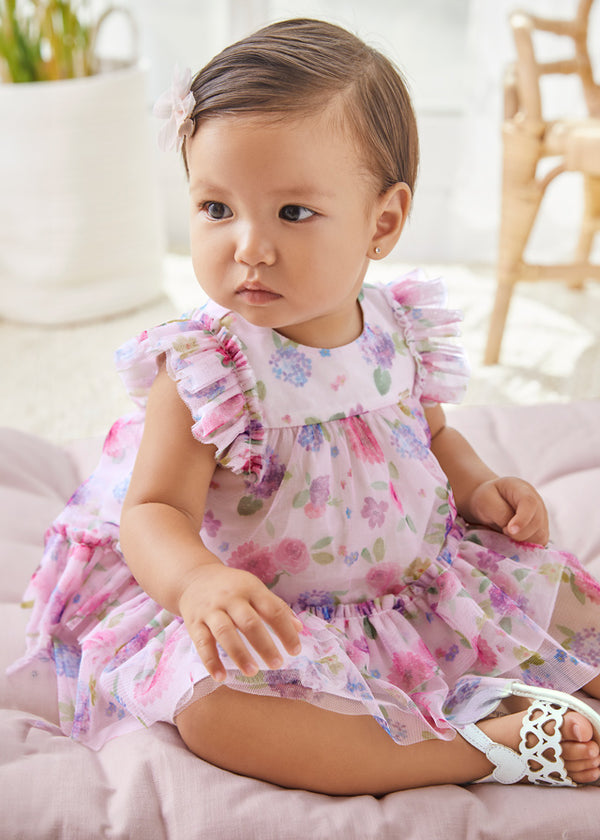 Baby wearing tulle printed dress, sitting.