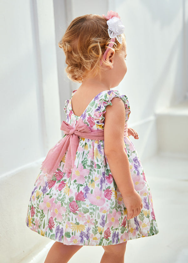 Baby girl wearing floral dress with tulle sash, back.